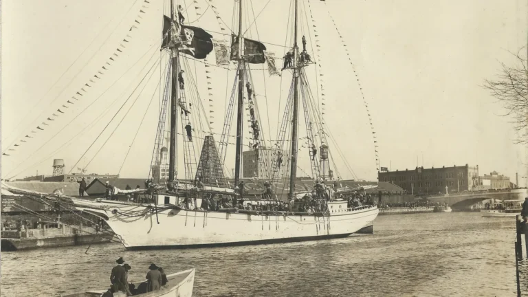 Vintage photograph of the Jose Gasparilla I, a pirate ship replica, used in Tampa's Gasparilla Festival. The ship is adorned with pirate flags and festive decorations, docked by the water with onlookers in boats and along the shore.