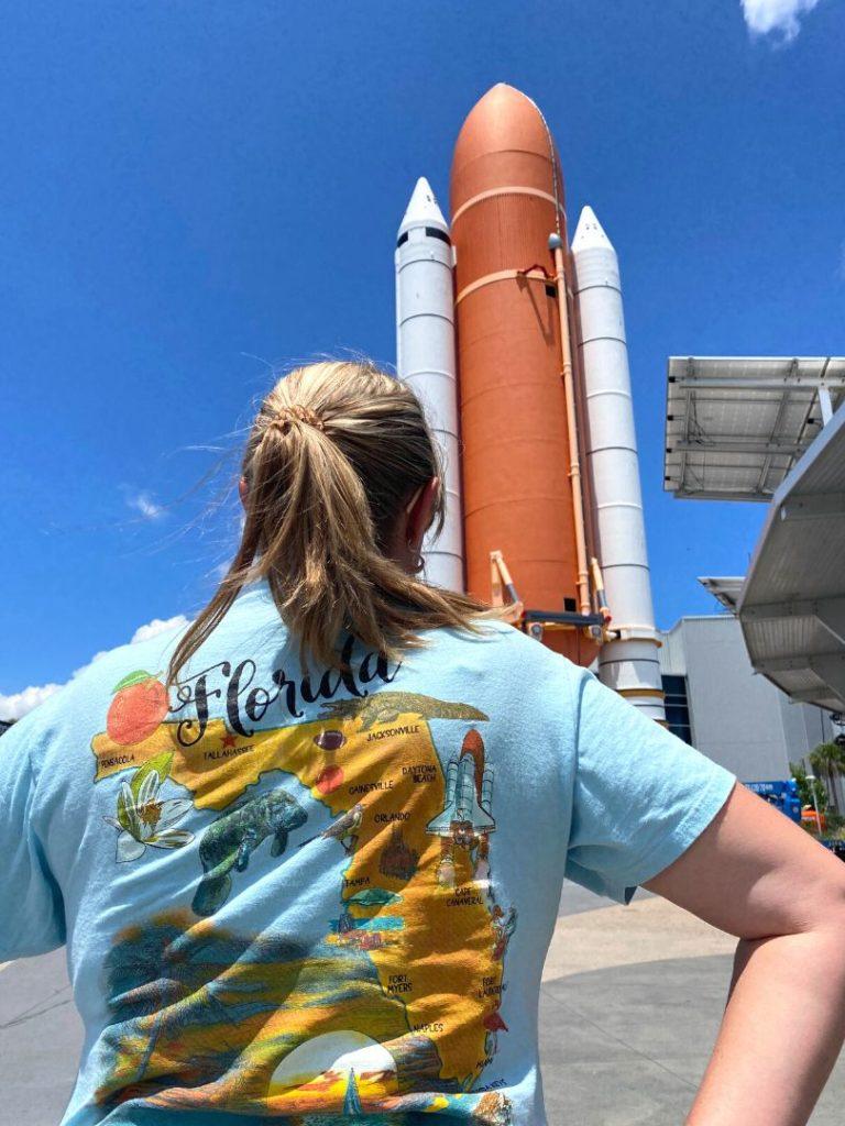 Woman standing with her back to the camera and the Atlantis Space Shuttle facade in front of her at Kennedy Space Center Visitors Complex 