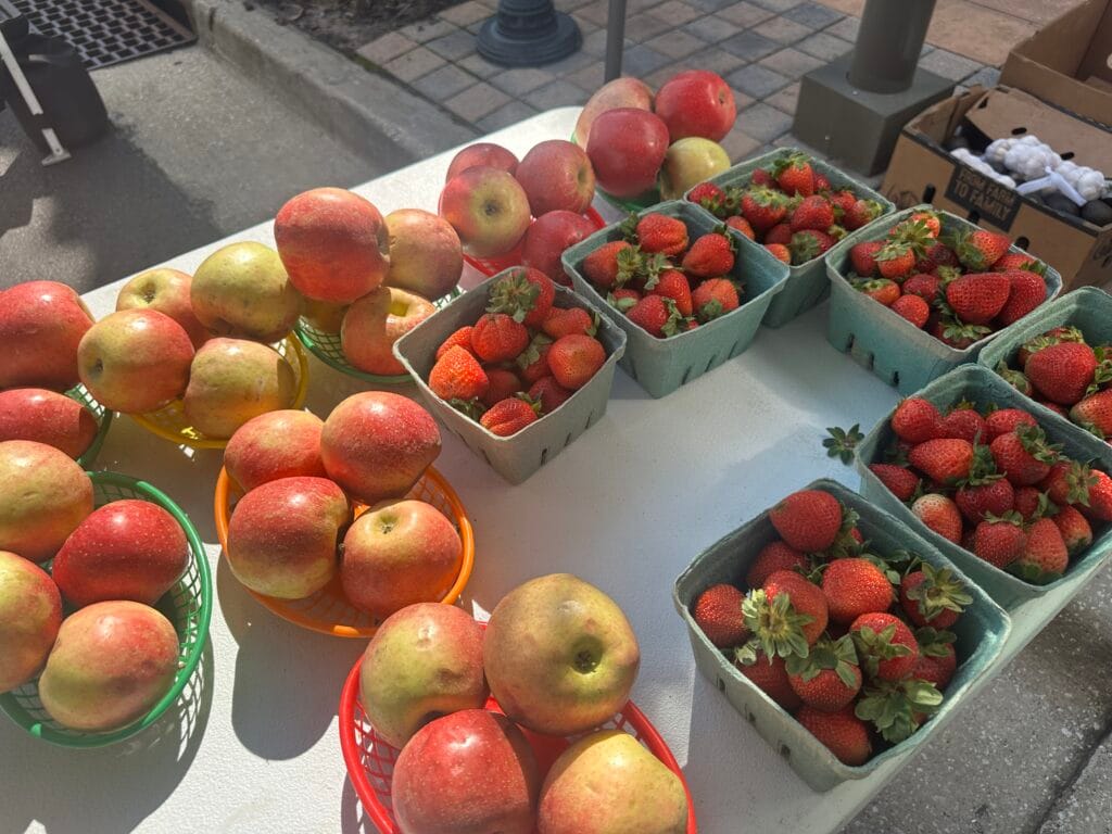 Bushels of strawberries and apples for sale at the Fresh Market at Wiregrass.