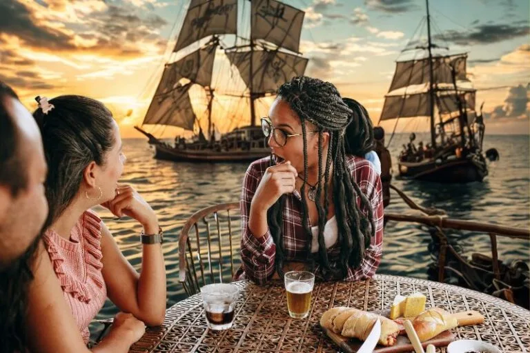 Gasparilla Tampa Bay Brunches three adults at table for brunch with pirate ships in background - image created by Dani Meyering with canva pro images