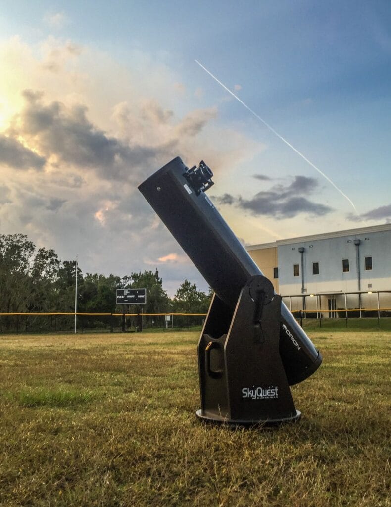 one of MOSI's SkyQuest telescopes sitting in an open field pointed at the sky