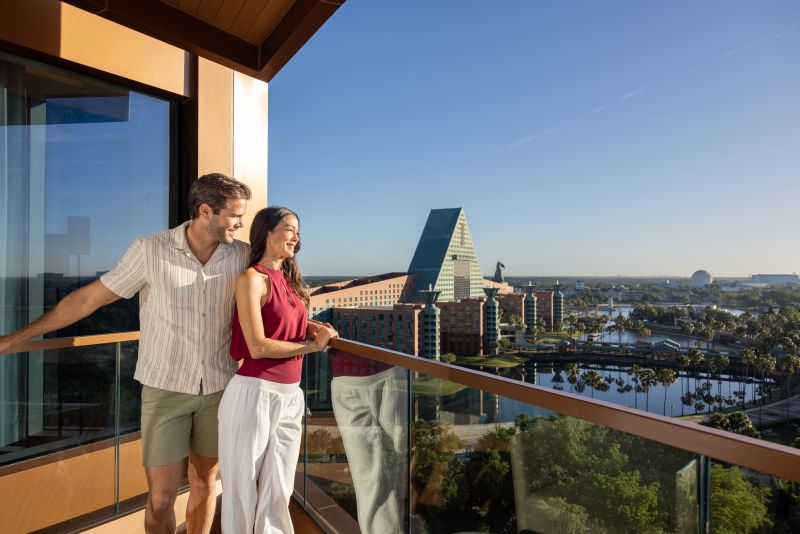 a couple looking out from their beautiful balcony at Swan and Dolphin Resort